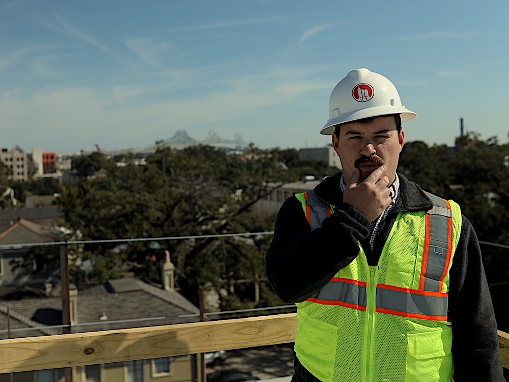 Man in hard hat and vest standing on top of a building | How to recognize payment issues on a construction project Man in hard hat and vest standing on top of a building | How to recognize payment issues on a construction project