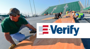 E-verify logo over image of construction workers in Florida stadium