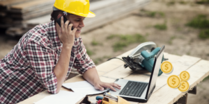 Photo of construction working on laptop and phone Photo of construction working on laptop and phone