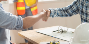 Prime contractor and subcontractor shaking hands across a table