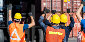 Photo of construction workers facing away from camera with fists raised