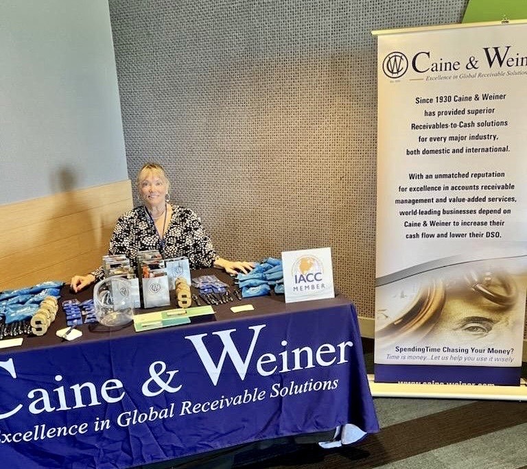 Lisa Newberg sits behind a Caine & Weiner branded table