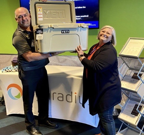 Barry Dambrowski with Emser Tile holding his prize, a YETI cooler, with Kathleen Quill from HighRadius