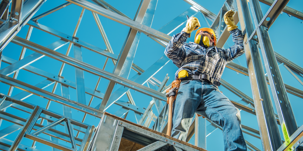 Photo taken from below of a construction worker standing on steel framing.